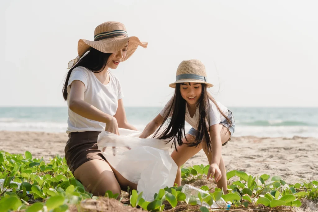 mother and daughter collecting plastic waste at the beach