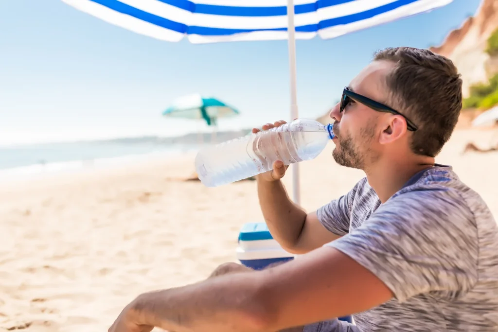 man drinking water on the beach